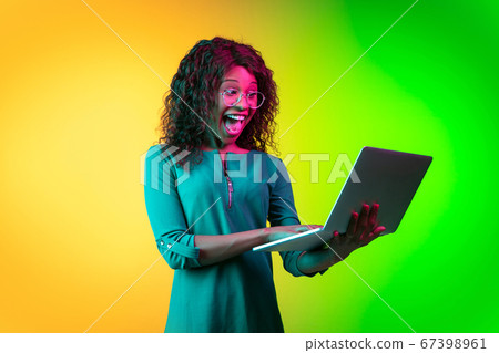 African-american young woman's portrait isolated on gradient yellow-green background in neon light African-american young woman's portrait isolated on gradient yellow-green background in neon light 67398961