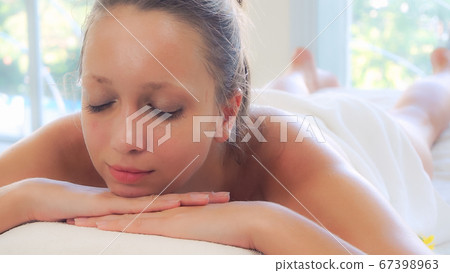 Relaxed young woman lying on spa bed for massage. Relaxed young woman lying on spa bed for massage. 67398963