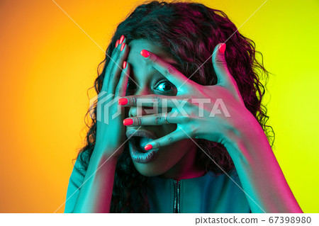 African-american young woman's portrait isolated on gradient yellow-green background in neon light African-american young woman's portrait isolated on gradient yellow-green background in neon light 67398980