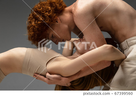 Portrait of beautiful redhead couple isolated on grey studio background. Concept of beauty, skin care, fashion and style Portrait of beautiful redhead couple isolated on grey studio background. Concept of beauty, skin care, fashion and style 67399560
