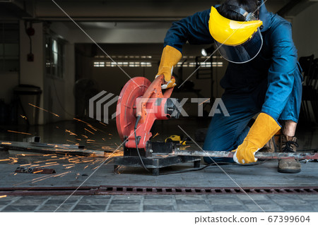 Professional mechanic is cutting steel metal. 67399604