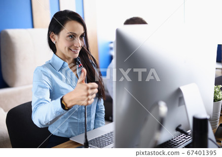 Woman holds thumbs up and communicates on an online call. Woman holds thumbs up and communicates on an online call. 67401395