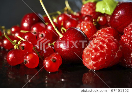 delicious and juicy red raspberries and cherries on a black table 67401502