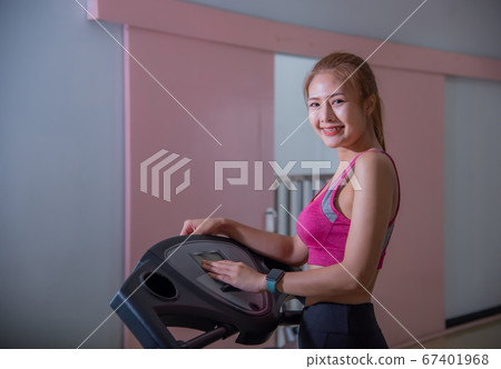 Full length profile shot of a young woman running on a treadmill in the gym. Young woman workout in gym healthy lifestyle. Full length profile shot of a young woman running on a treadmill in the gym. Young woman workout in gym healthy lifestyle. 67401968