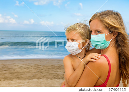 Mother, child in face masks on tropical sea beach Mother, child in face masks on tropical sea beach 67406315