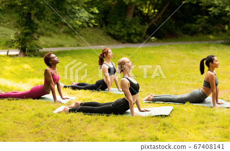 Group of diverse girls doing cobra yoga pose on their morning practice at green park Group of diverse girls doing cobra yoga pose on their morning practice at green park 67408141