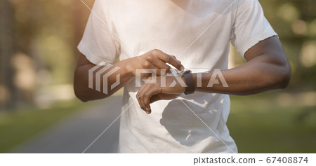 African american runner checking time on his smartwatch African american runner checking time on his smartwatch 67408874