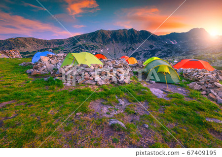 Camping place with colorful tents at sunset, Retezat mountains, Romania Camping place with colorful tents at sunset, Retezat mountains, Romania 67409195