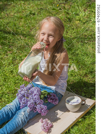 Little girl with cup of milk on nature Little girl with cup of milk on nature 67409562