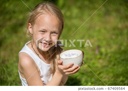 Little girl with cup of milk on nature 67409564