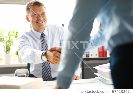 Businessman shakes hands with woman in office closeup 67410241