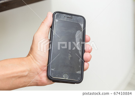 Hand with a broken smartphone 67410884