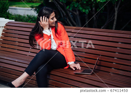 Beautiful Asian brunette working with laptop online Beautiful Asian brunette working with laptop online 67411450