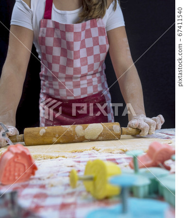 Girl rolling the dough with a rolling pin on the table. Baker background 67411540