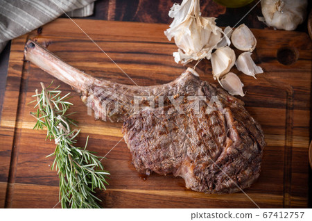 grilled tomahawk steak on wooden board 67412757