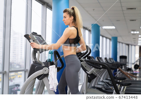 Young woman working out on orbi track at gym exercising Young woman working out on orbi track at gym exercising 67413448