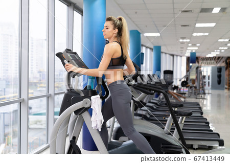 Young woman working out on orbi track at gym exercising Young woman working out on orbi track at gym exercising 67413449