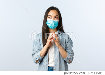 Social distancing lifestyle, covid-19 pandemic and people emotions concept. Sly and creative asian woman in medical mask, scheming secret plan, steeple fingers and look dreamy upper left corner Social distancing lifestyle, covid-19 pandemic and people emotions concept. Sly and creative asian woman in medical mask, scheming secret plan, steeple fingers and look dreamy upper left corner 67414505