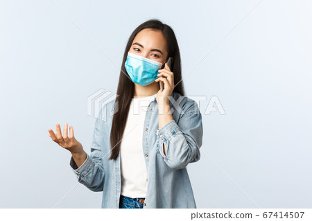 Social distancing lifestyle, covid-19 pandemic and people emotions concept. Modern asian girl in medical mask talking to friend on mobile phone, having conversation or making order Social distancing lifestyle, covid-19 pandemic and people emotions concept. Modern asian girl in medical mask talking to friend on mobile phone, having conversation or making order 67414507