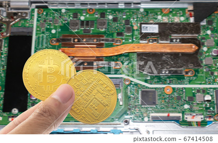 Bitcoin holding in hand with motherboard blurred background. 67414508