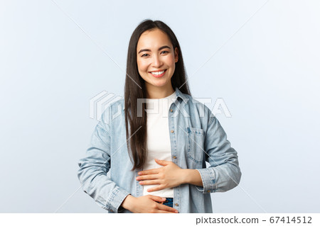 Lifestyle, people emotions and beauty concept. Pleased smiling asian woman rubbing her belly, being full after eating, pleased feeling in stomach from drinking yoghurt Lifestyle, people emotions and beauty concept. Pleased smiling asian woman rubbing her belly, being full after eating, pleased feeling in stomach from drinking yoghurt 67414512