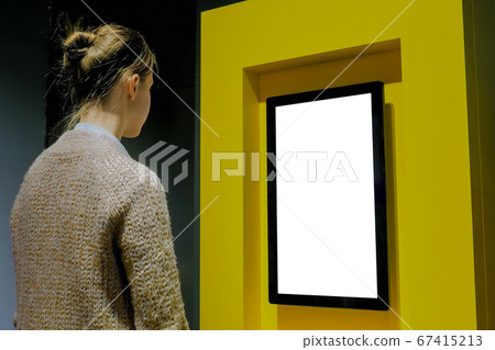 Woman looking at blank white display wall at exhibition - white screen concept 67415213