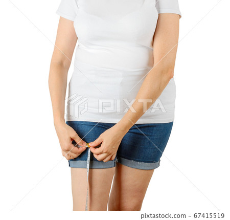 Caucasian mature adult woman begins to gain weight and measures her thigh with a measuring tape. Caucasian mature adult woman begins to gain weight and measures her thigh with a measuring tape. 67415519