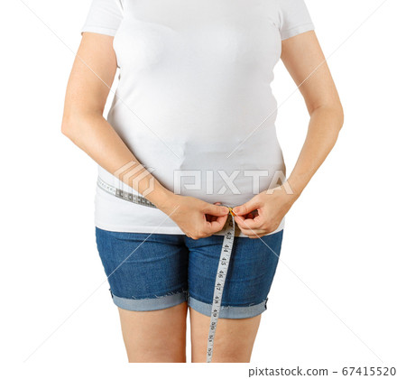 Caucasian mature adult woman begins to gain weight and measures her hips with a measuring tape. Caucasian mature adult woman begins to gain weight and measures her hips with a measuring tape. 67415520
