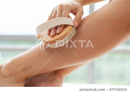 Cellulite treatment, woman arm holding dry brush to top of her leg. Cellulite treatment, woman arm holding dry brush to top of her leg. 67416039