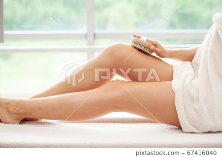 Cellulite treatment, woman arm holding dry brush to top of her leg. Cellulite treatment, woman arm holding dry brush to top of her leg. 67416040