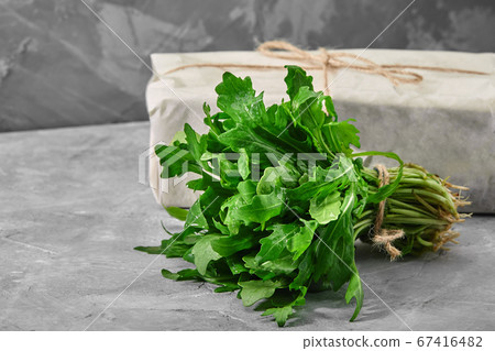 Fresh arugula leaves in a cup on concrete background. Healthy and fresh salad. Organic and natural food concept. Light background. Flat lay. Fresh arugula leaves in a cup on concrete background. Healthy and fresh salad. Organic and natural food concept. Light background. Flat lay. 67416482