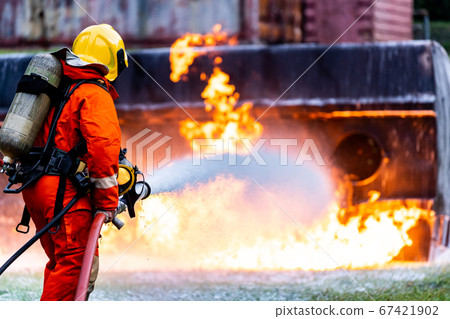 Firefighters spraying down fire flame from oil 67421902