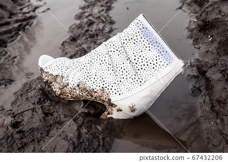 Dirty white high-heel shoe on the ground Dirty white high-heel shoe on the ground 67432206