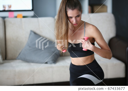Woman holds dumbbells in her hands and does exercises Woman holds dumbbells in her hands and does exercises 67433677