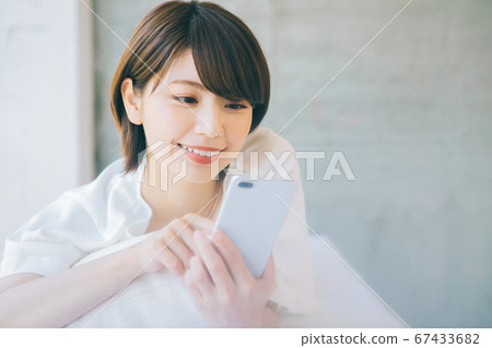 躺下並使用智能手機的女性(*請避免在結婚活動和婚戀機構等網站和應用上使用智能手機) 躺下並使用智能手機的女性(*請避免在結婚活動和婚戀機構等網站和應用上使用智能手機) 67433682
