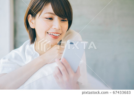 躺下並使用智能手機的女性(*請避免在結婚活動和婚戀機構等網站和應用上使用智能手機) 躺下並使用智能手機的女性(*請避免在結婚活動和婚戀機構等網站和應用上使用智能手機) 67433683