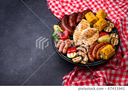 Grilled sausages, meat, and vegetables. 67433942