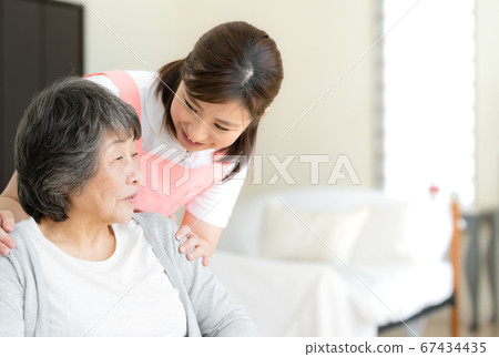 Caregiver who cares for a senior woman sitting in a wheelchair [home care] 67434435