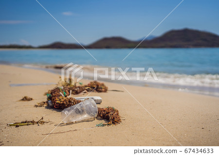 Man in gloves pick up plastic bags that pollute sea. Problem of spilled rubbish trash garbage on the beach sand caused by man-made pollution and environmental, campaign to clean volunteer in concept Man in gloves pick up plastic bags that pollute sea. Problem of spilled rubbish trash garbage on the beach sand caused by man-made pollution and environmental, campaign to clean volunteer in concept 67434633
