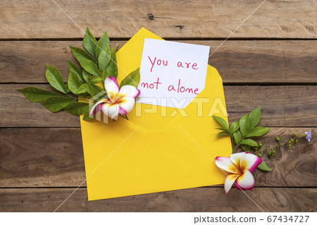 you are not alone message card handwriting in yellow envelope with flowers frangipani 67434727