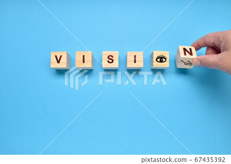 Man turning a die of the word VISION on a blue Man turning a die of the word VISION on a blue 67435392