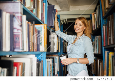 Blonde teacher searching book in the library in school Blonde teacher searching book in the library in school 67437305
