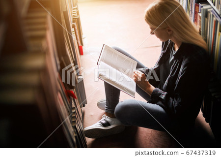 Young female student studying in the library Higher education. Student life 67437319