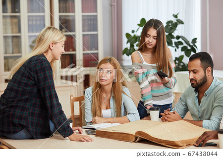 Diverse multiracial students spending leisure time in library with big old book 67438044