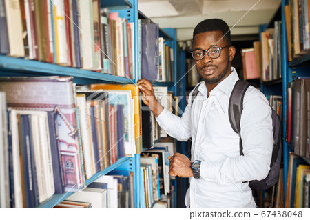 African american male college student preparing for exams in the library. 67438048
