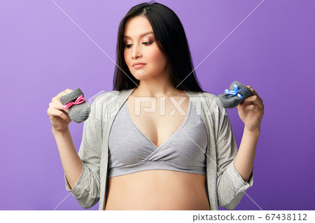 Baby booties for unborn child on the belly of pregnant woman Baby booties for unborn child on the belly of pregnant woman 67438112