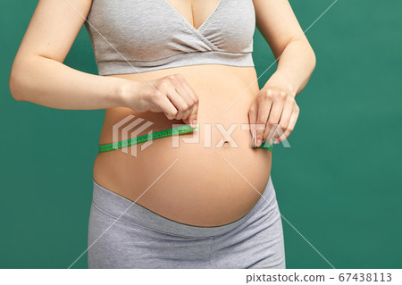 Pregnant woman measuring stomach with measuring tape Pregnant woman measuring stomach with measuring tape 67438113