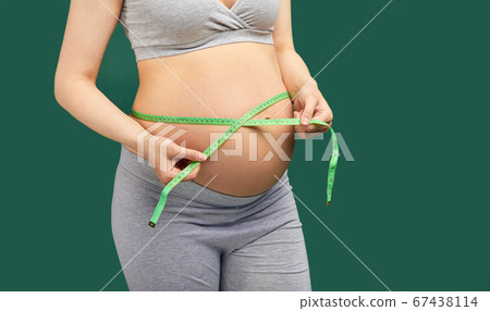 Pregnant woman measuring stomach with measuring tape Pregnant woman measuring stomach with measuring tape 67438114