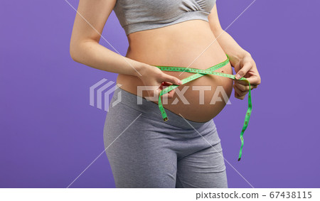 Pregnant woman measuring stomach with measuring tape Pregnant woman measuring stomach with measuring tape 67438115