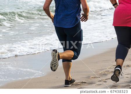Rear view of women running on the sand next to the 67438323